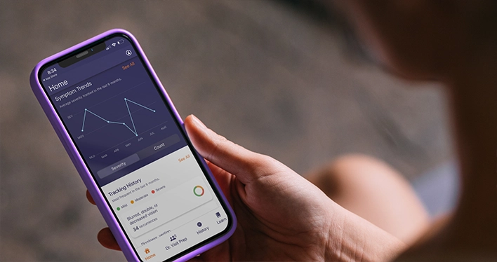 A person holds a smartphone displaying the MPN symptom tracker app