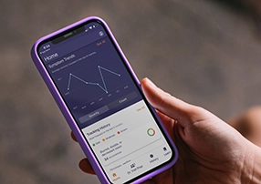 A person holds a smartphone displaying the MPN symptom tracker app